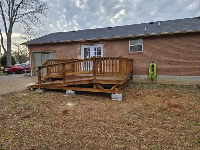 Rear view of a brown-stained 10x16 deck with railings and ramp attached to a brick home in Murfreesboro, Tennessee.