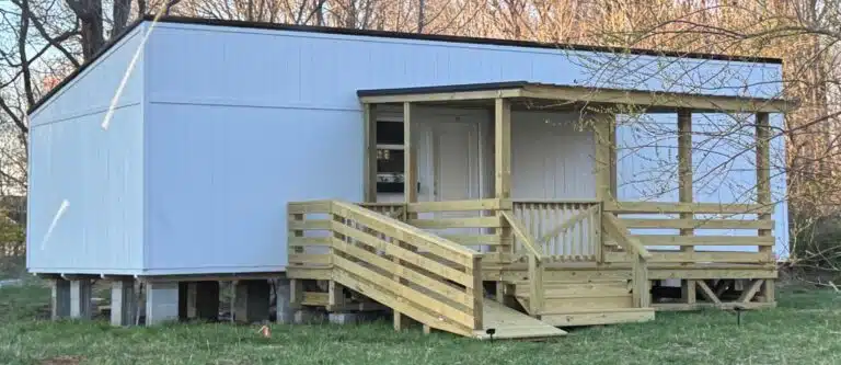 Side view of a 12x16 mobile home deck with a wooden ramp, railing, and covered entry in Alvaton, Kentucky.