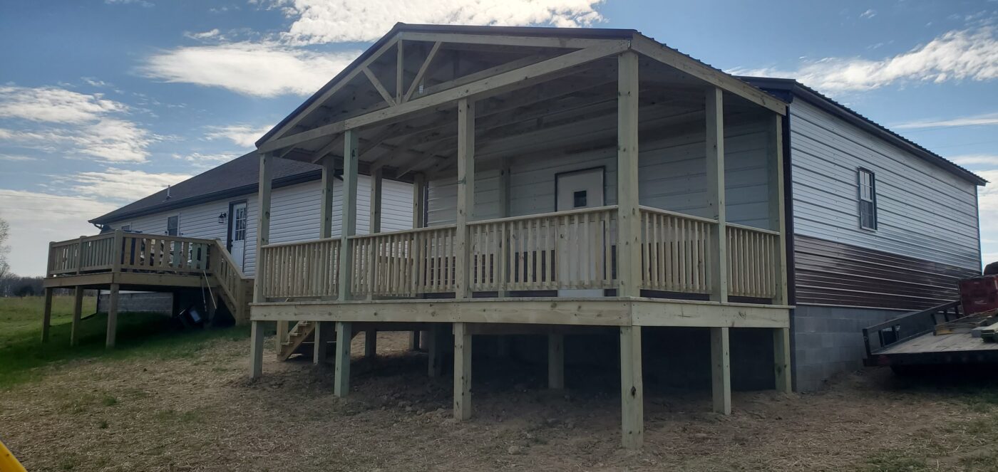 A newly built 12x24 A-frame porch with a covered roof and wooden railings attached to a metal-sided home in Lafayette, Tennessee.