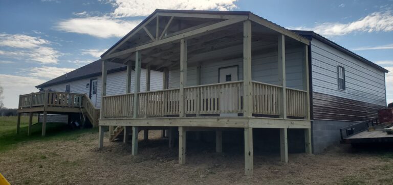 A newly built 12x24 A-frame porch with a covered roof and wooden railings attached to a metal-sided home in Lafayette, Tennessee.