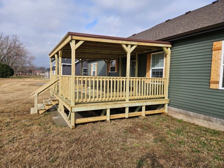 14x20 covered wooden porch with stairs and railings attached to a green home in Russellville, Kentucky.