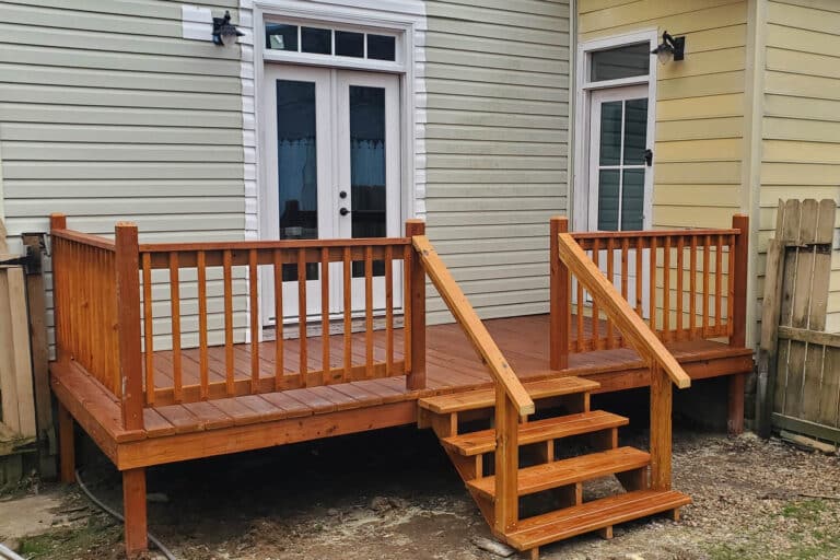 Rear view of an 8x16 cedar-stained deck attached to a light gray and yellow home in Springfield, Tennessee.