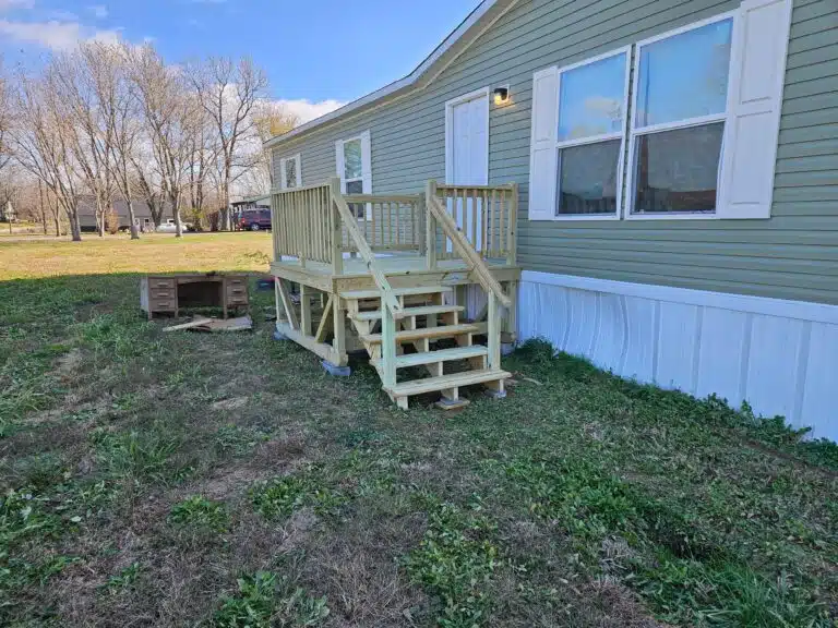 8x8 wooden deck with railings and stairs attached to a green mobile home in Garfield, Kentucky.