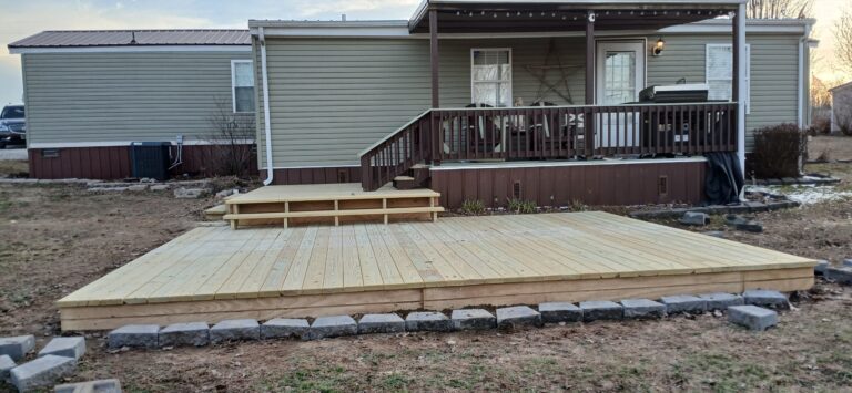Side view of a two-section wooden deck with steps leading to a covered porch on a beige home in Beaver Dam, Kentucky.