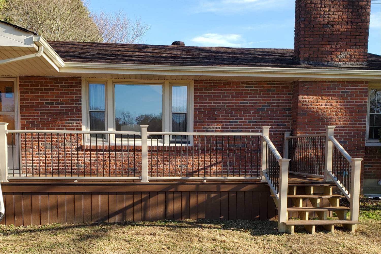 Deck attached to brick house with steps and vinyl railing