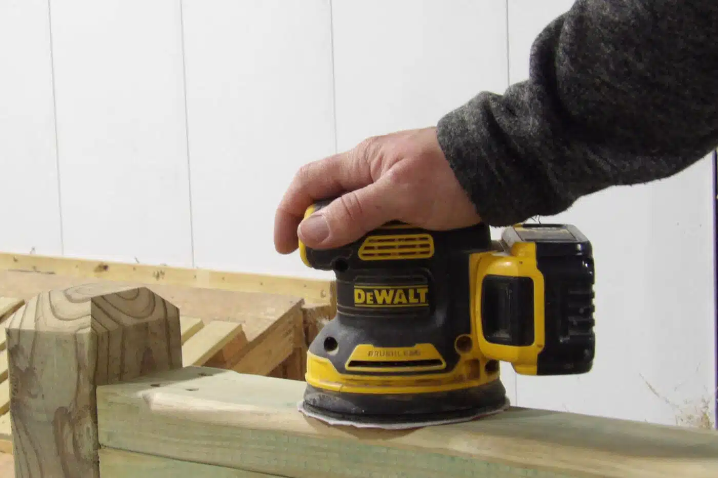 man sanding piece of wood for front porch