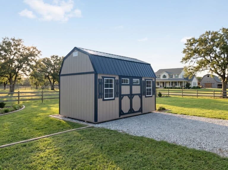 Gray lofted garden shed with double doors, windows, and a small ramp on a gravel pad.