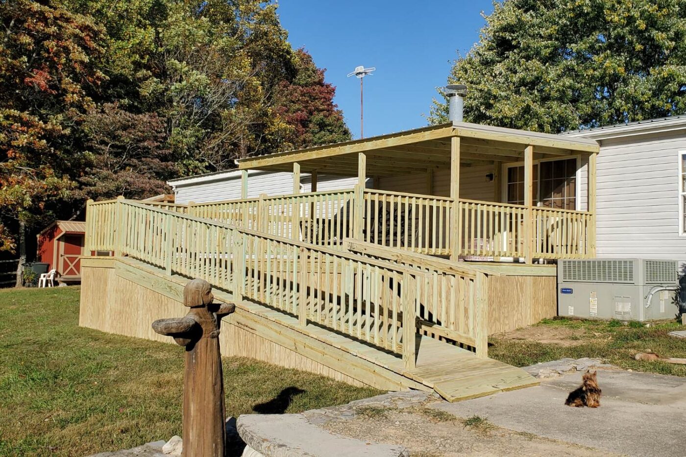 Prebuilt Porches in Kentucky 16 Large wooden porch outside home with extensive ramp. A dog sits on the driveway outside porch