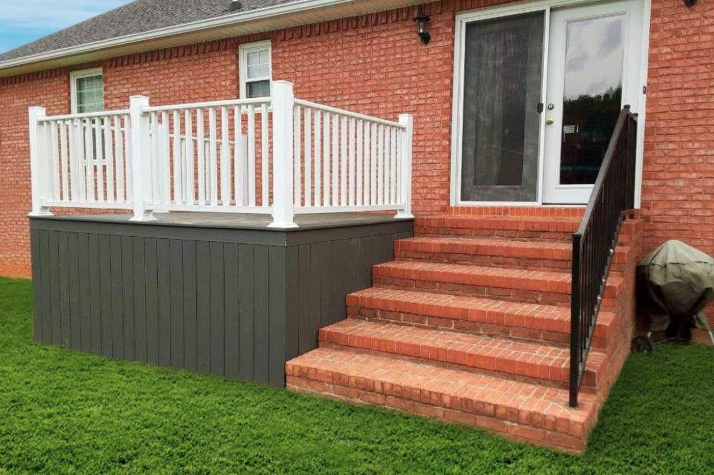 Small house deck outside bright brick Kentucky home with white vinyl railing and gray floor