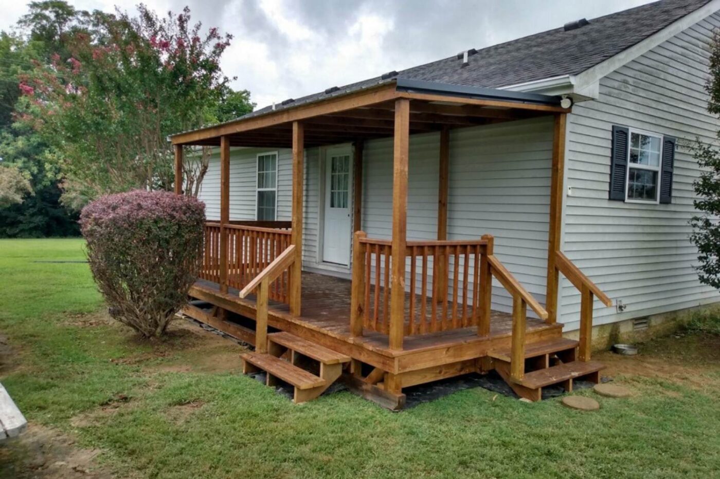 Prebuilt Porches in Kentucky 8 Wooden house porch attached to white home with two sets of stairs and trees to side and in background