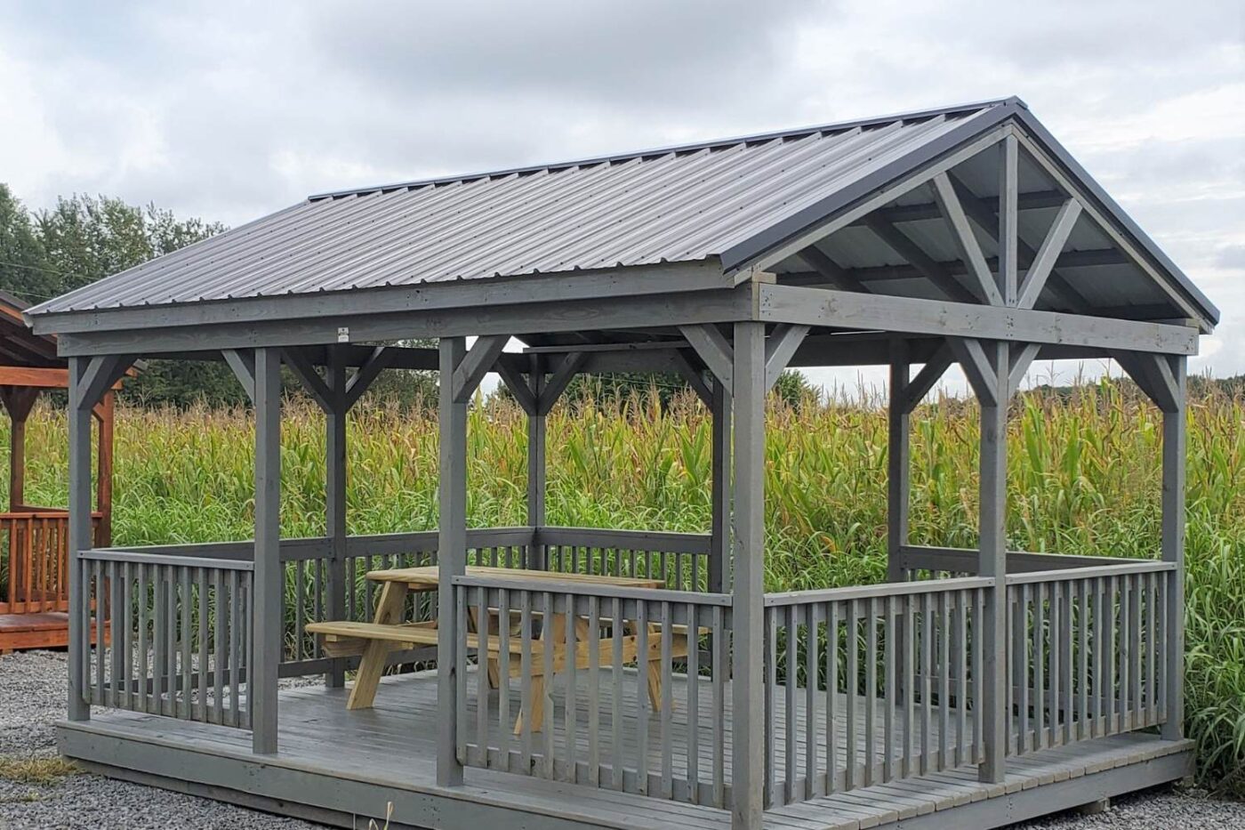 Prebuilt Porches in Kentucky 11 Gray pavilion with picnic bench underneath in front of corn field in Kentucky