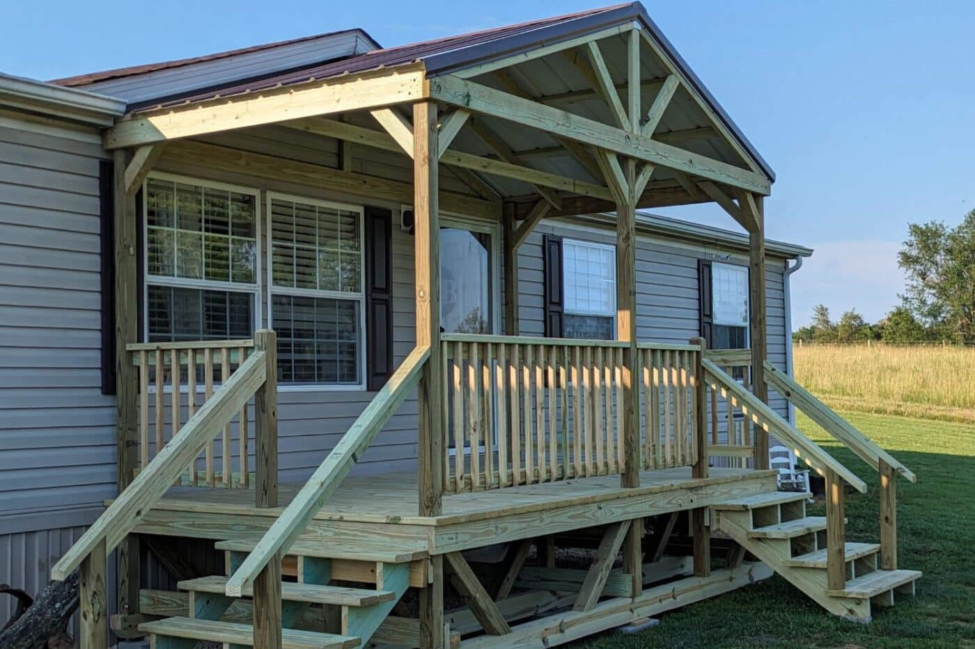 Wooden porch with steps, railings, and overhang attached to home