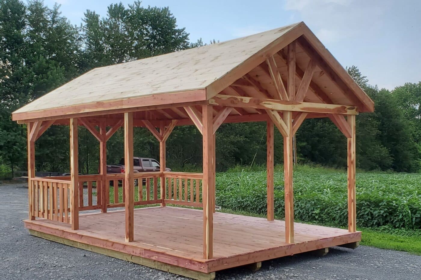 Portable light-stained wooden pavilion on gravel road besides field