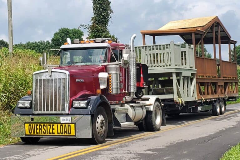 Decks on back of truck with oversize load sign on road