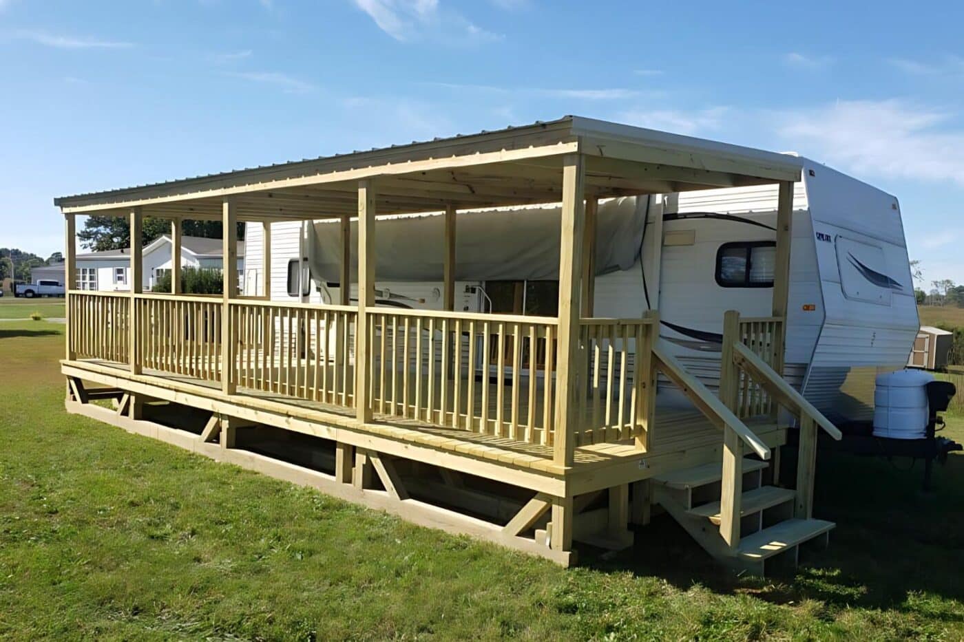 Extensive RV deck attached to RV in a field with overhang, steps, and railings