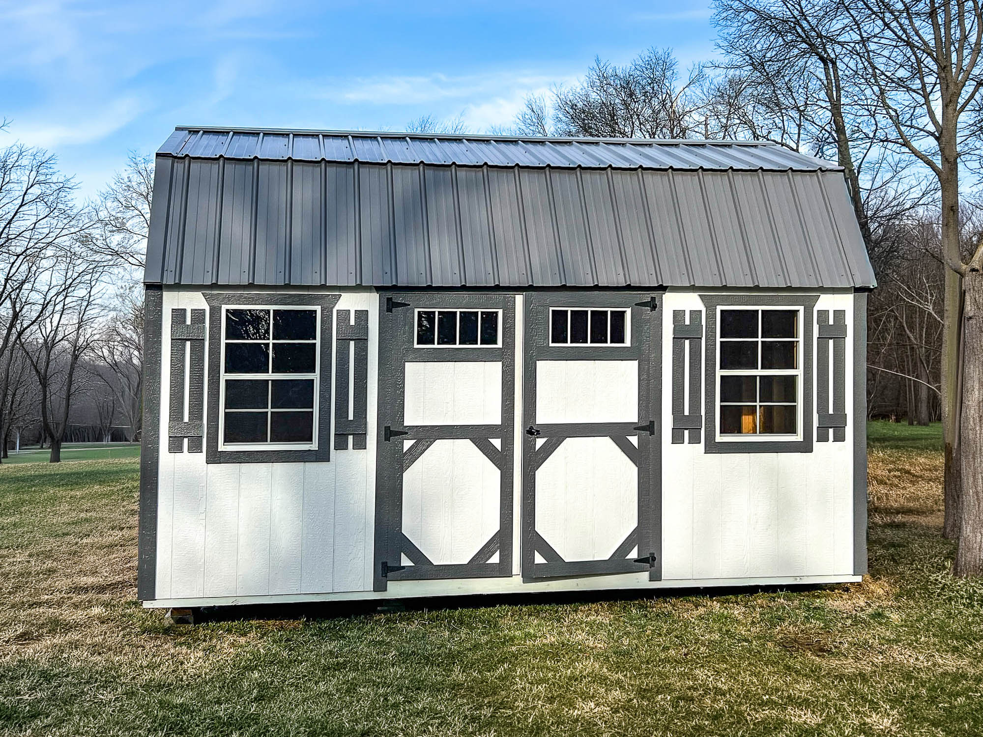 Sheds for Sale In TN & KY 2 White garden shed with gray trim, double doors, two windows, shutters, and a gray metal roof.