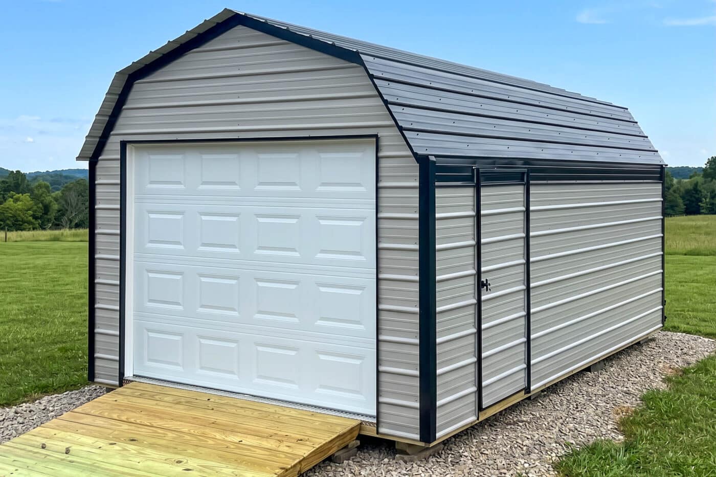 Gray metal garage shed with black trim, white overhead door, side entry door, and front ramp.