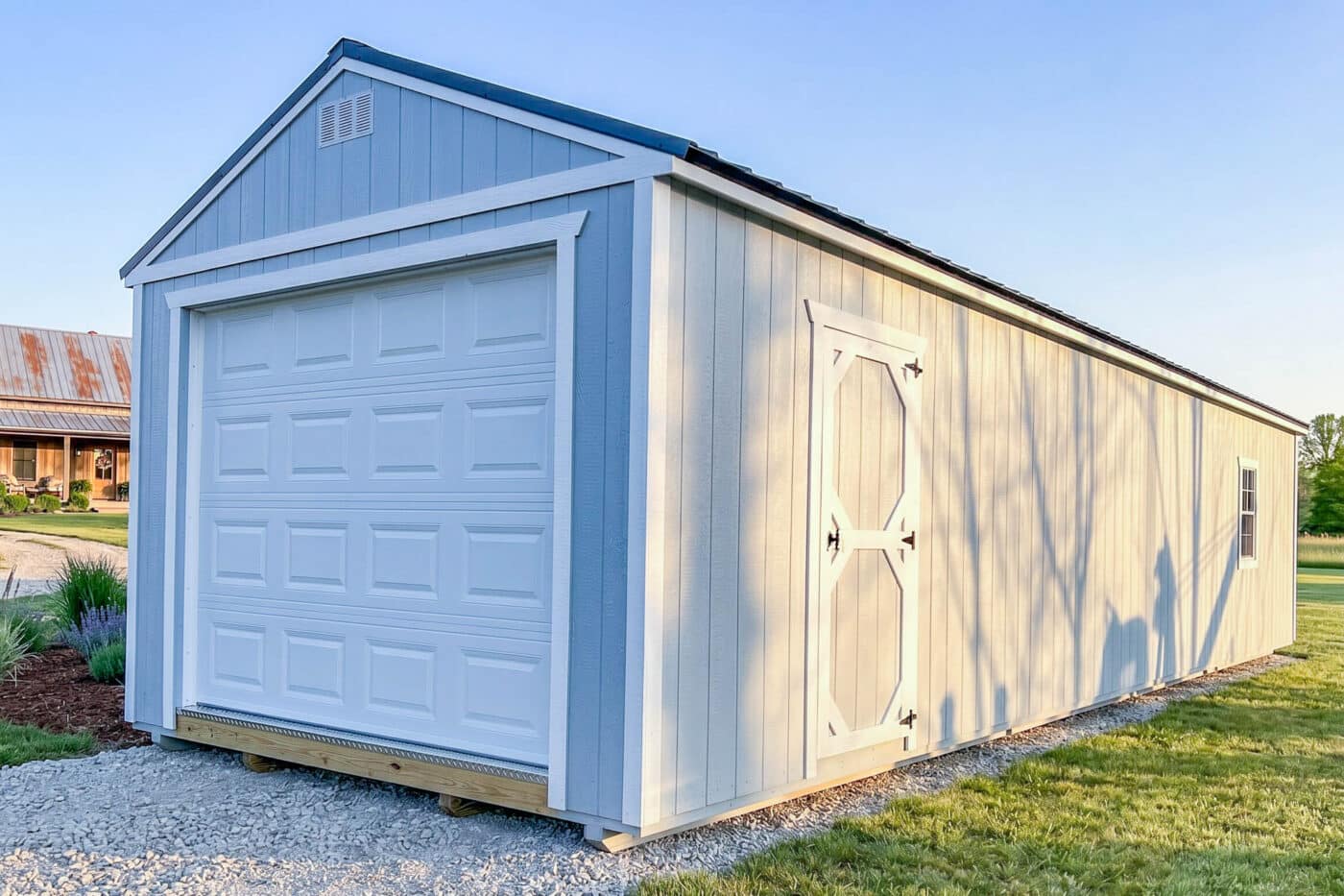 Light gray portable garage with white trim, an overhead garage door, side entry door, and window.